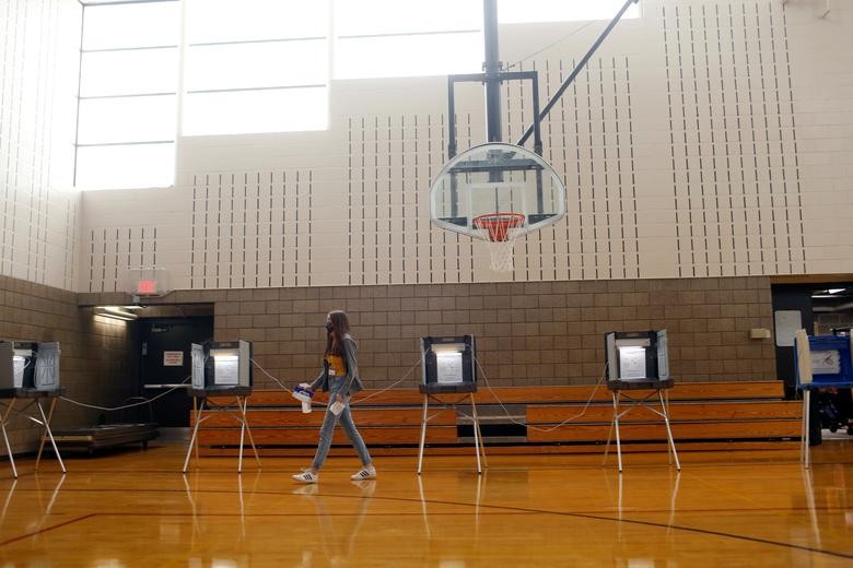 A volunteer sprays down tables and voting booths periodically while people vote at Whittier Community Center during the primary election in Minneapolis, Minnesota.  REUTERS/Nicole Neri